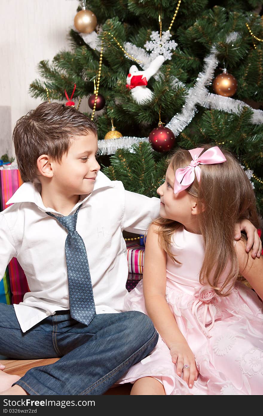 Merry girl and boy with gifts near a new-year tree. Merry girl and boy with gifts near a new-year tree