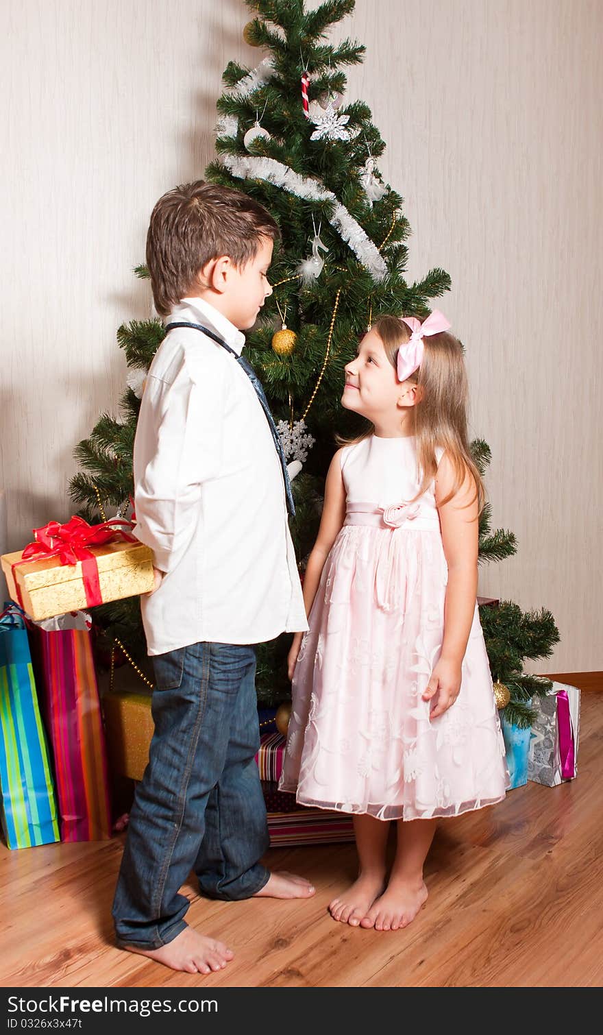 Merry girl and boy with gifts near a new-year tree. Merry girl and boy with gifts near a new-year tree