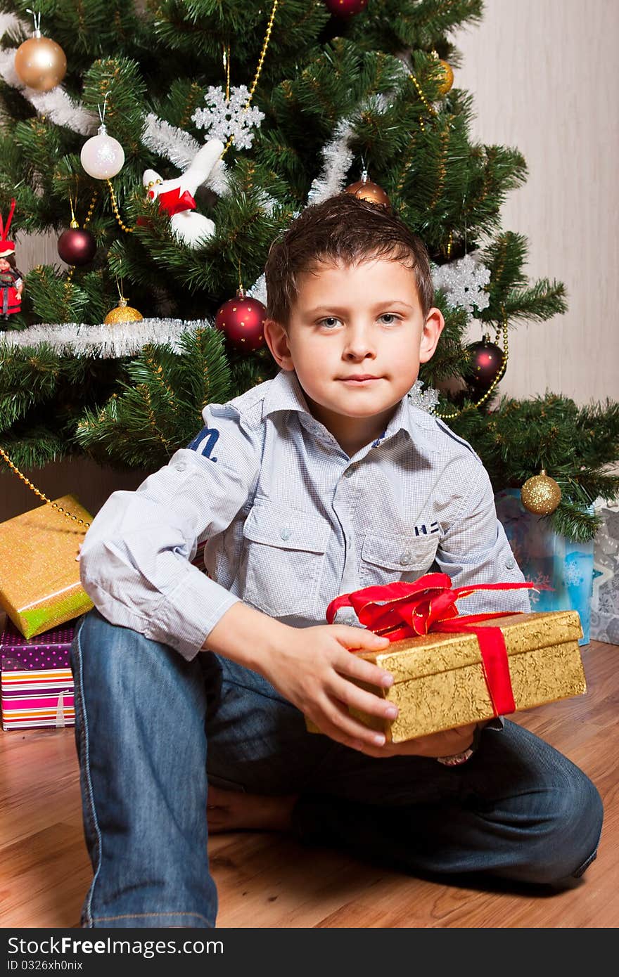 Merry boy with gifts near a new-year tree. Merry boy with gifts near a new-year tree