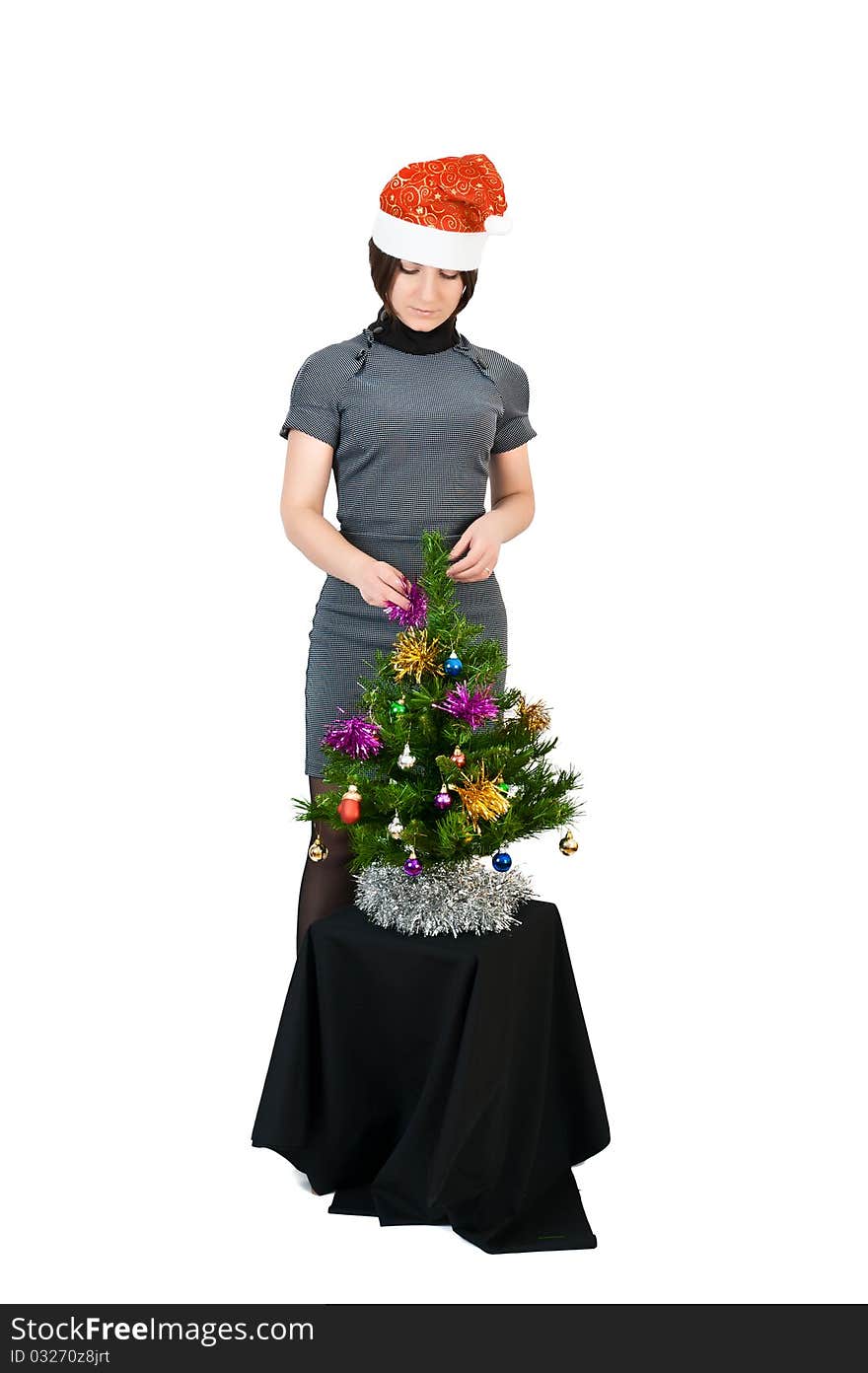 Young girl in the hat of Santa Claus dresses up Christmas tree