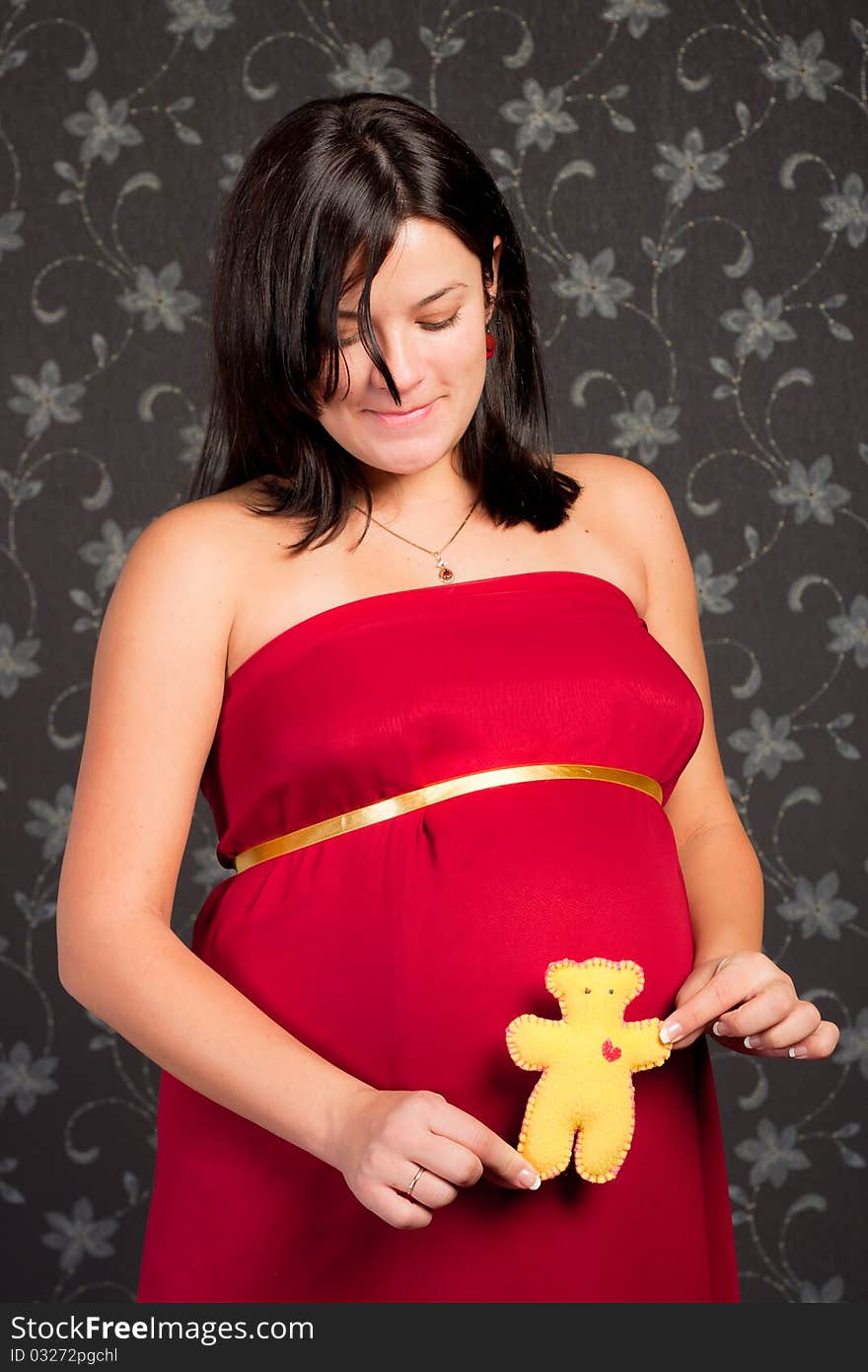 Beautiful pregnant woman with plush bear toy