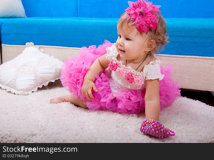 The nice little girl in a pink dress sits and smiles. The nice little girl in a pink dress sits and smiles