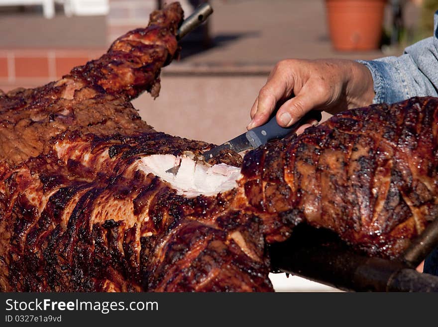 The first cut of a grilled pig on an open fire.