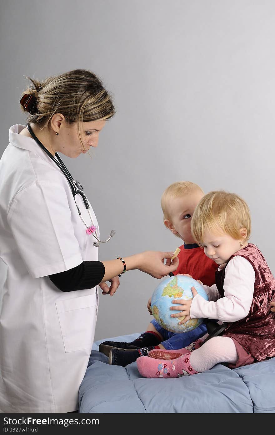 Young doctor communicating in hospital with baby boy and girl and preparing for examination. Young doctor communicating in hospital with baby boy and girl and preparing for examination