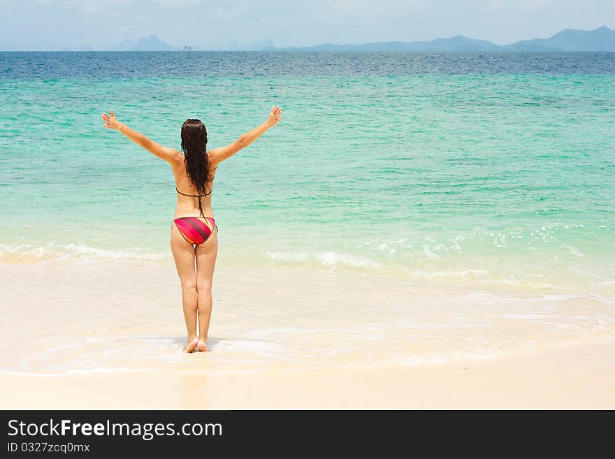 Young woman standing on beach with arms raised. Young woman standing on beach with arms raised