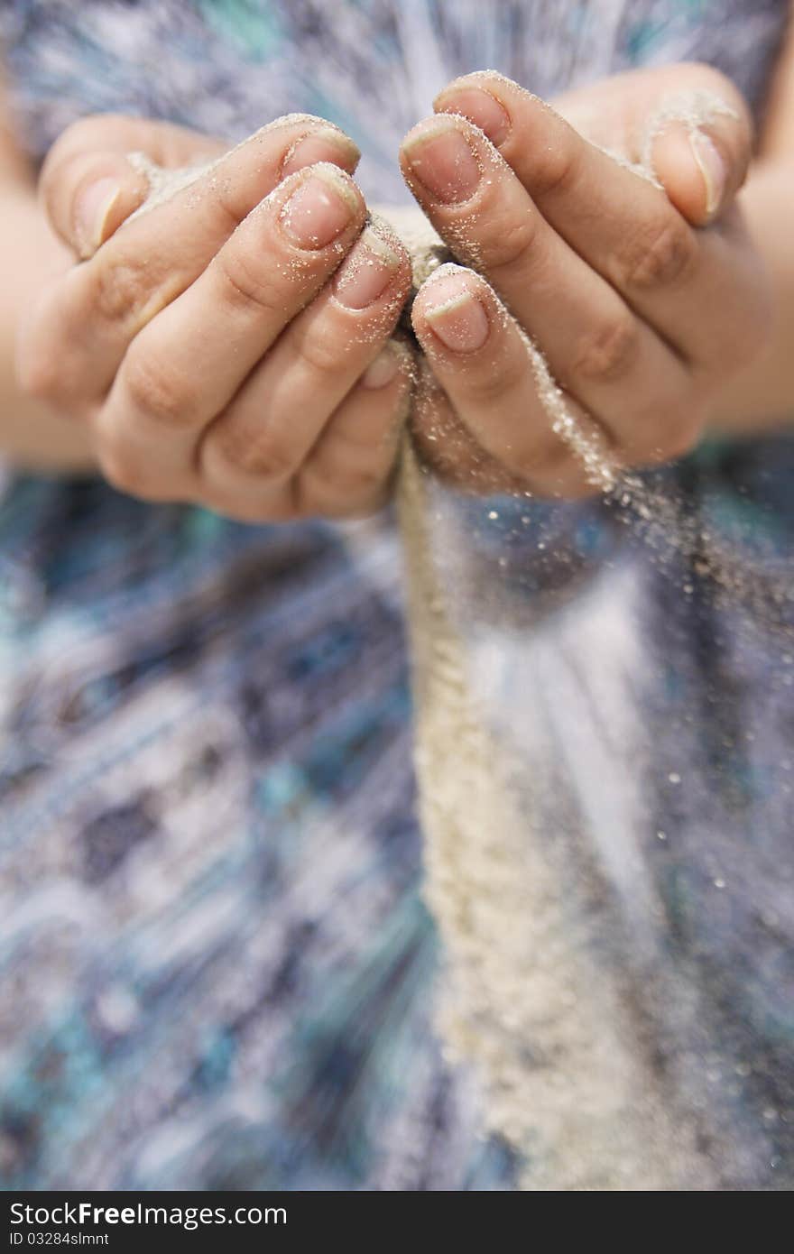 Girls standing on the beach with sand running through her hands. Girls standing on the beach with sand running through her hands.