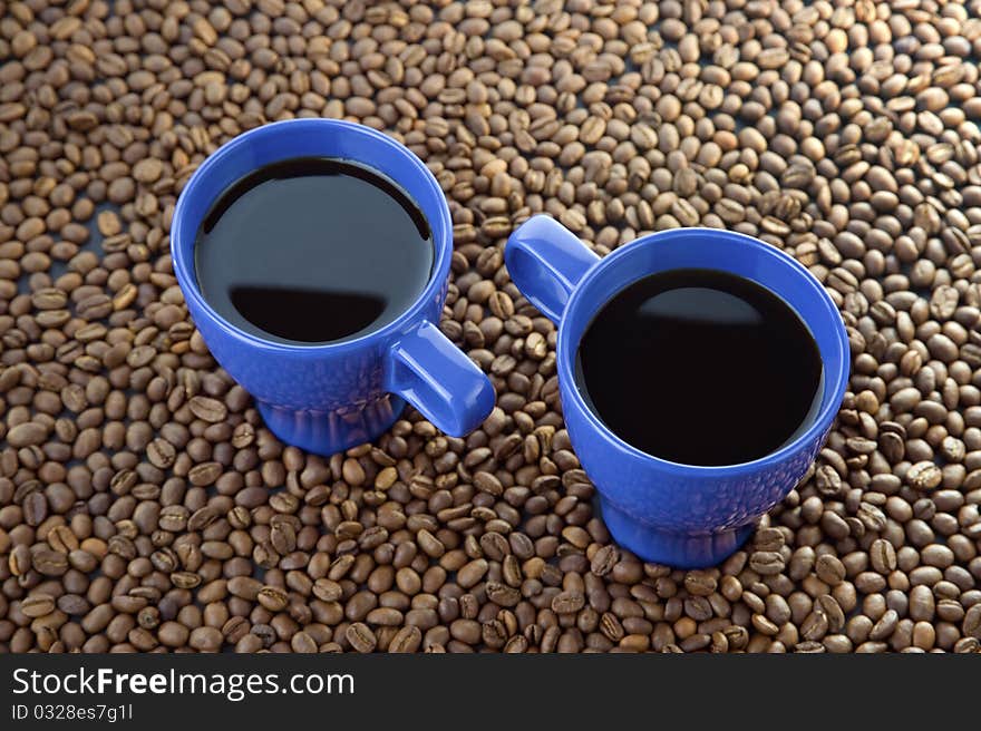 Coffee time - two mugs filled with hot coffe with smoke coffee beans and wood background. Coffee time - two mugs filled with hot coffe with smoke coffee beans and wood background