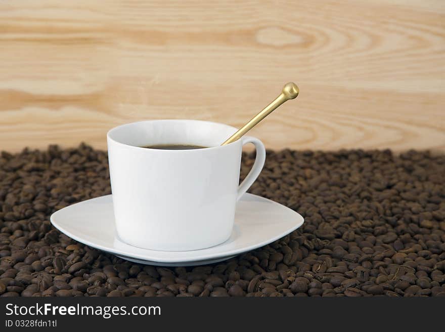 Coffee time - mug filled with hot coffe with smoke coffee beans and wood background. Coffee time - mug filled with hot coffe with smoke coffee beans and wood background