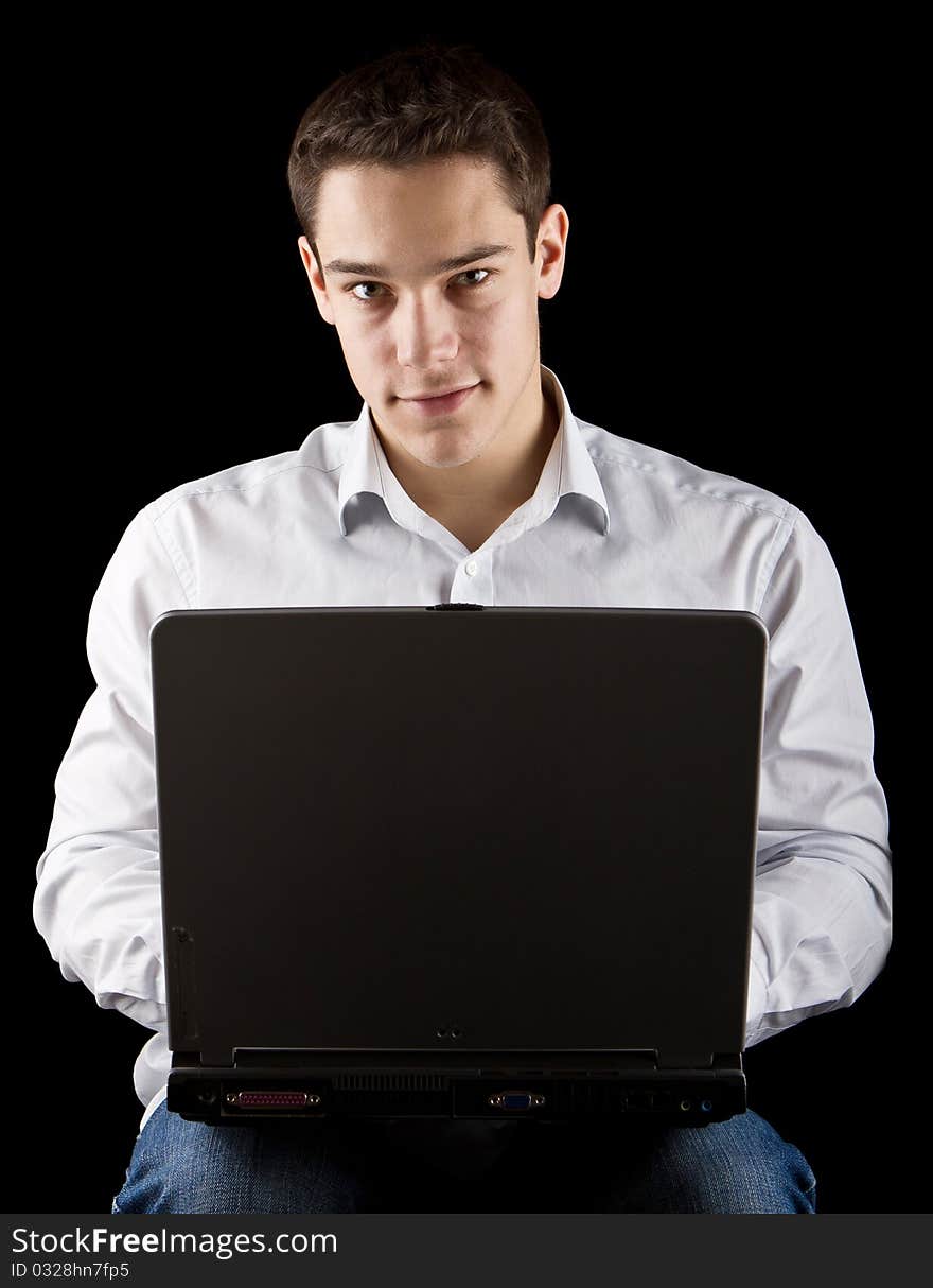 Young handsome man working on his laptop over black background. Young handsome man working on his laptop over black background.