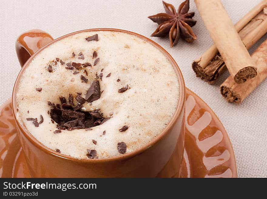 Cappuccino in a brown ceramic cup with spice.