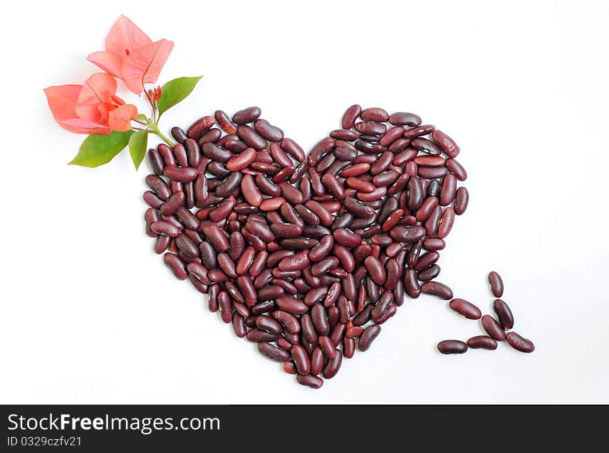 Heart made of beans with pink flowers and an arrow though on a white background