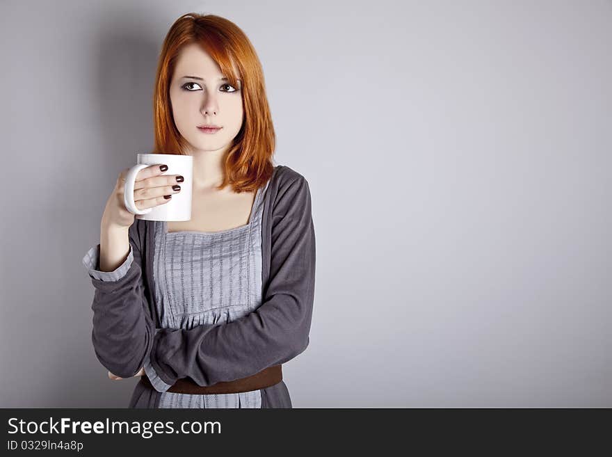 Portrait of red-haired girl with cup. Studio shot.