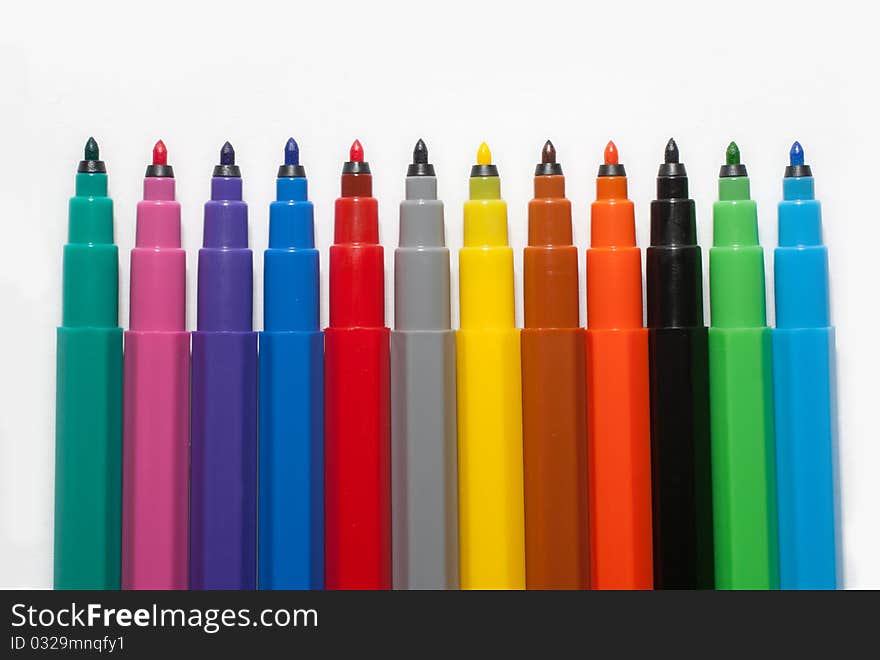 A row of coloured felt-tip pens on white background. A row of coloured felt-tip pens on white background