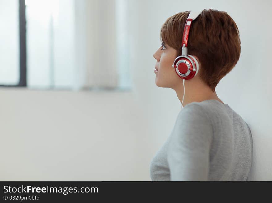 Young adult caucasian woman with headphones at home. Horizontal shape, side view, copy space. Young adult caucasian woman with headphones at home. Horizontal shape, side view, copy space