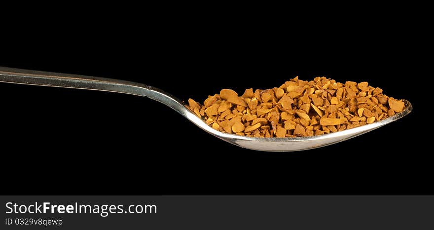 Instant coffee on a spoon isolated on black background