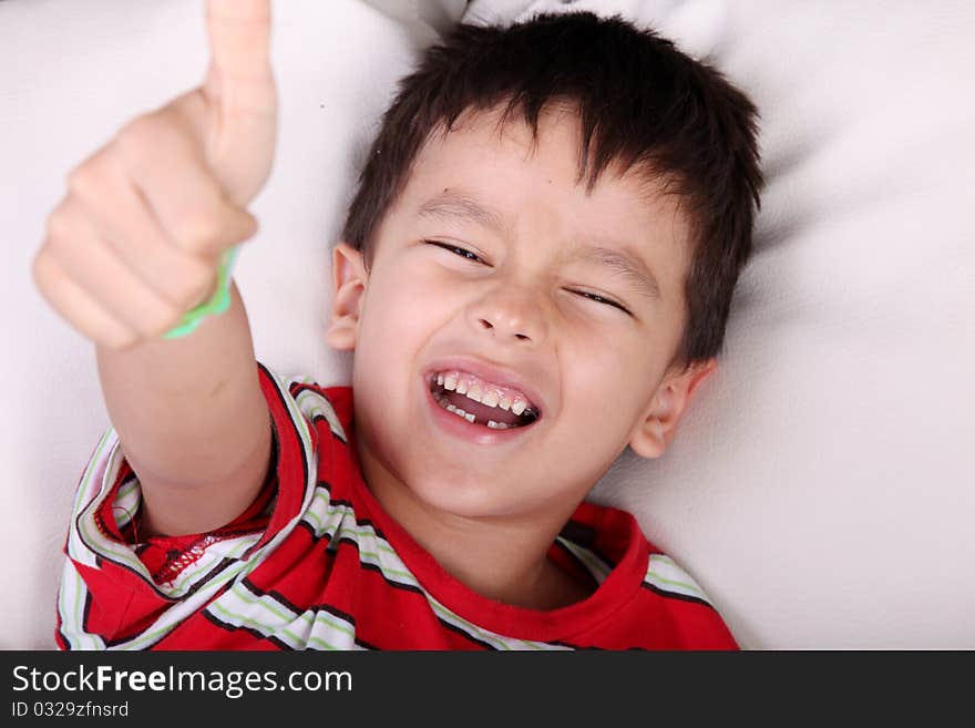 Happy boy lying and showing his thumb as a sign of positivism