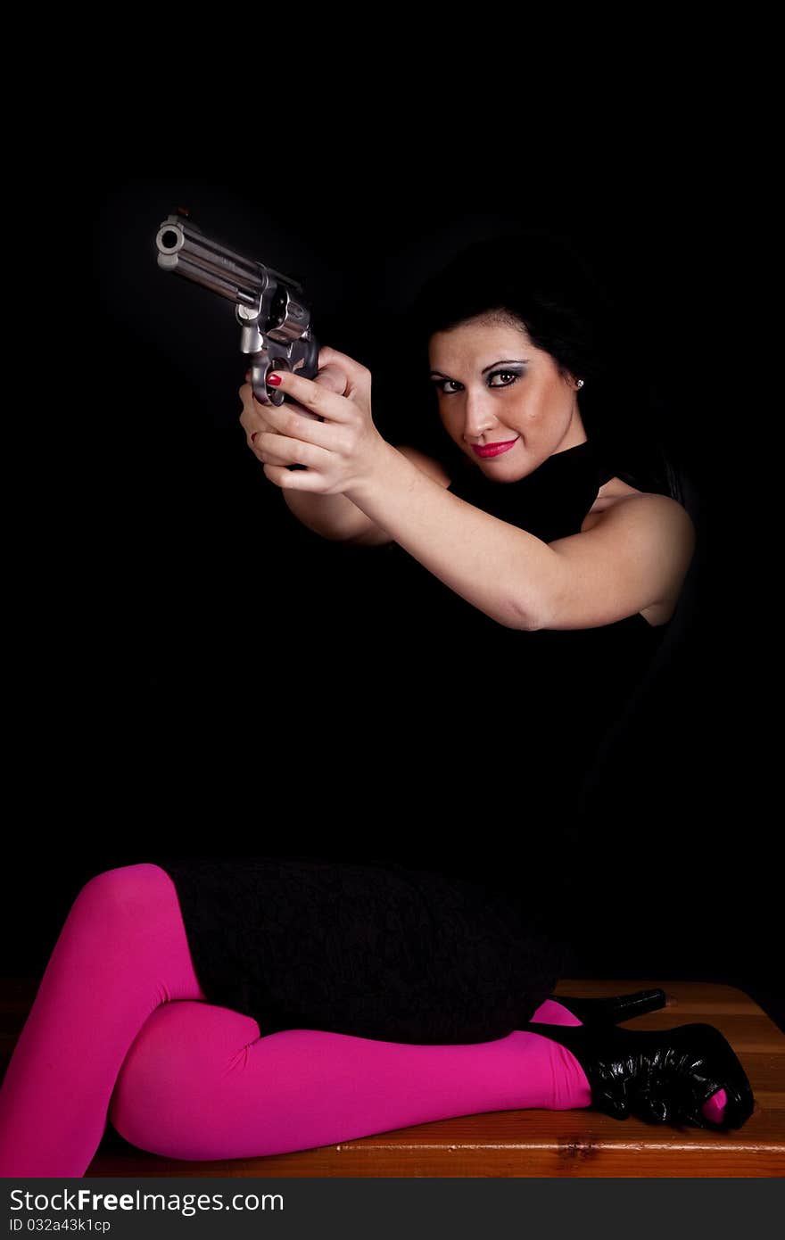 A woman wearing black and pink tights pointing a pistol at someone with a serious expression on her face. A woman wearing black and pink tights pointing a pistol at someone with a serious expression on her face.