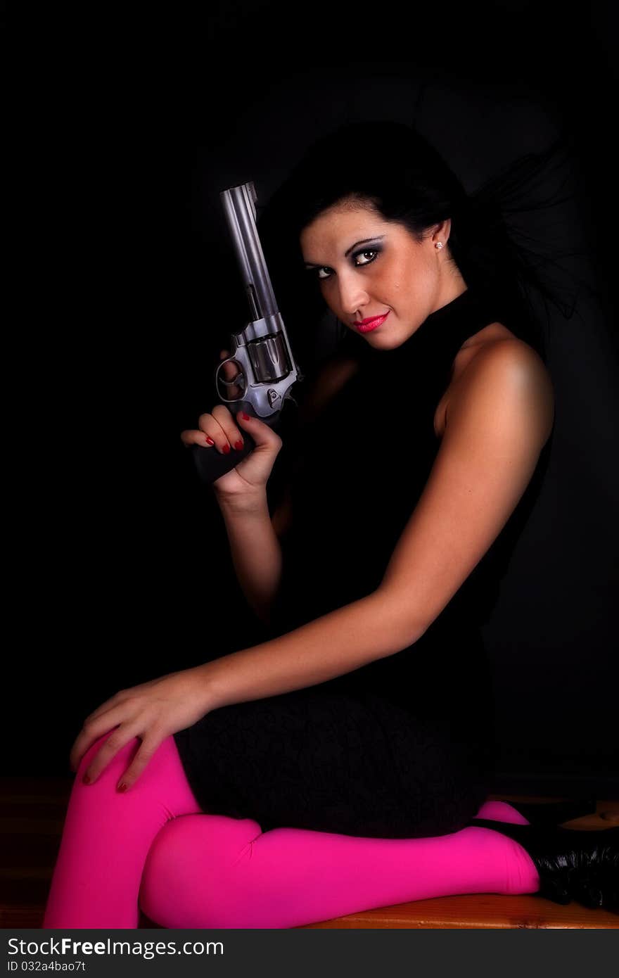 A woman in black and pink tights holding a pistol while she holds the gun up. A woman in black and pink tights holding a pistol while she holds the gun up.