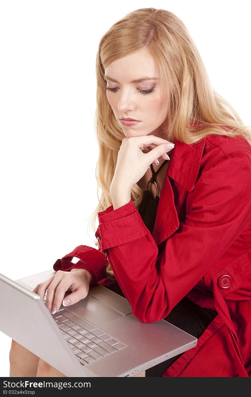 A woman in a red coat with a serious expression on her face looking at something on her computer. A woman in a red coat with a serious expression on her face looking at something on her computer.