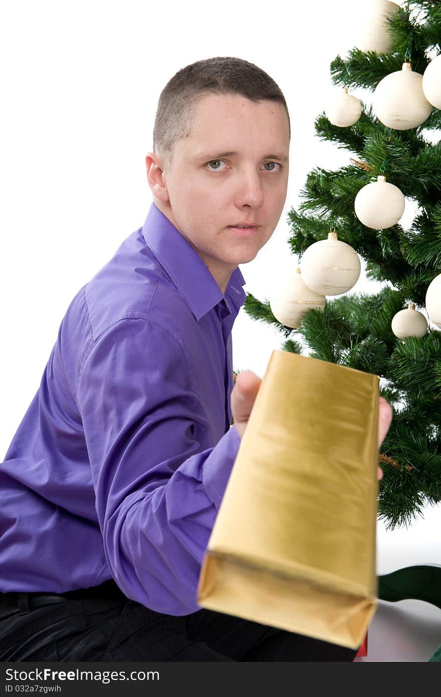 Man under christmas tree is giving a gift