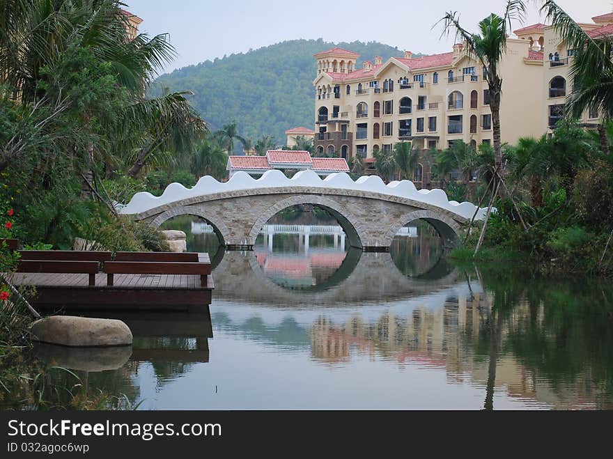 View of a beautiful bridge over a pond inside a tropical residential area. View of a beautiful bridge over a pond inside a tropical residential area