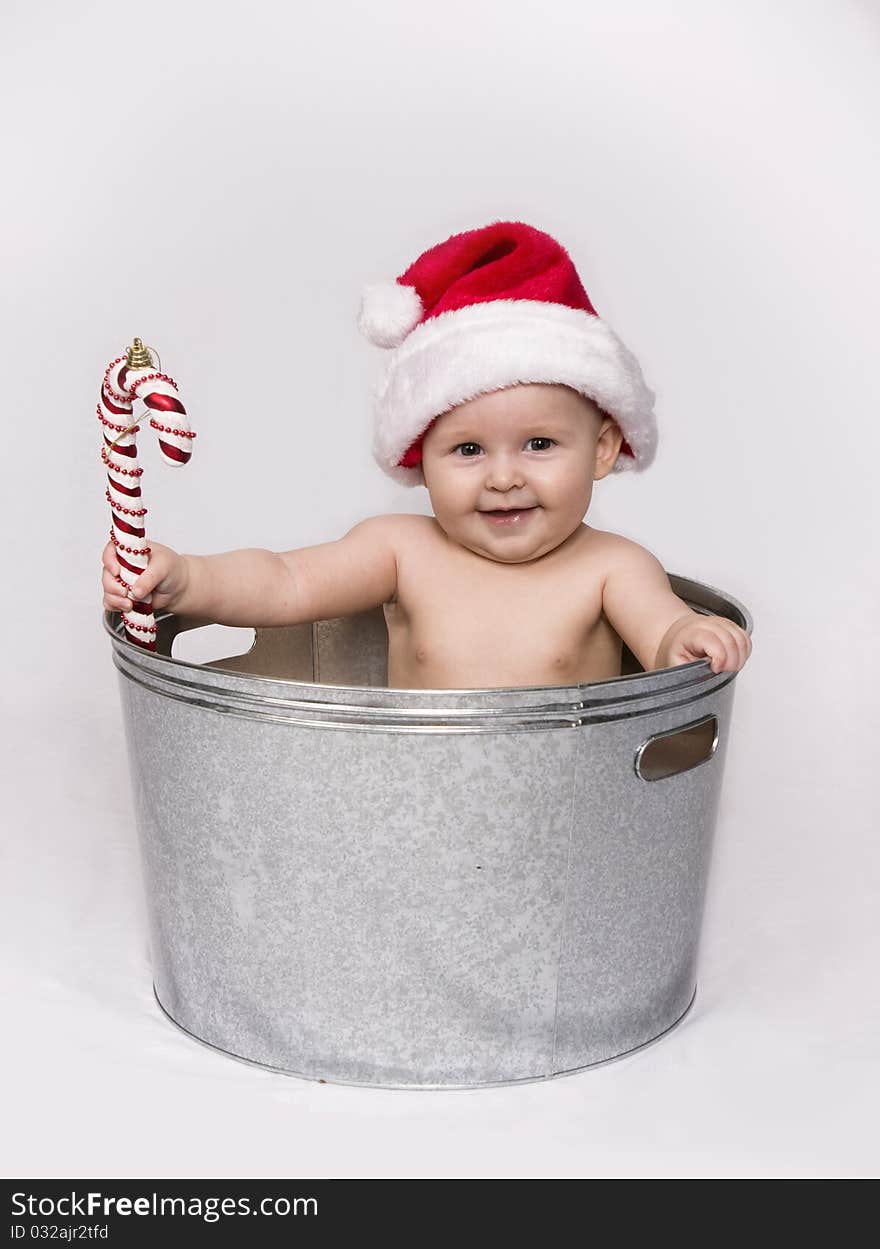 Baby In Basin Holding Candy Cane And Wearing Santa