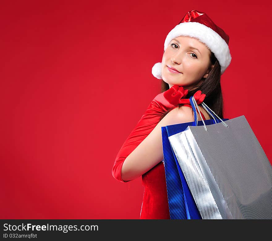 Portrait of a young charming girl dressed as Santa with a bag of shopping in their hands. Happy New Year!