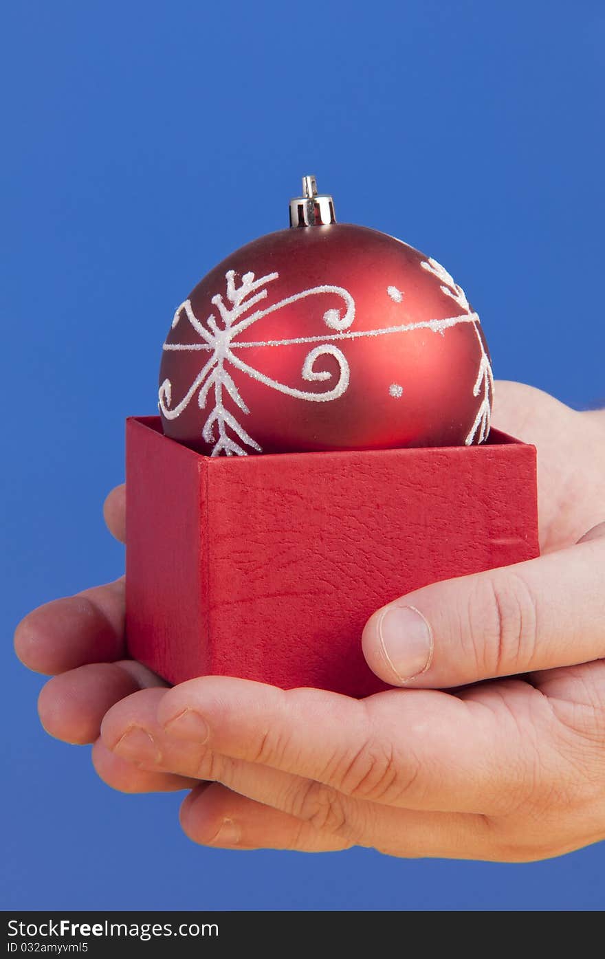 Red box with a christmass decorative ball holded in palms. Red box with a christmass decorative ball holded in palms