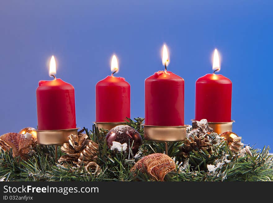 Red lit candles and christmas decorations. shooted in studio on a blue background. Red lit candles and christmas decorations. shooted in studio on a blue background