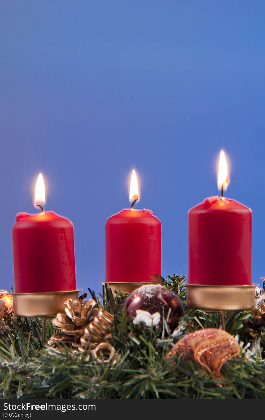 Red lit candles and christmas decorations. shooted in studio on a blue background. Red lit candles and christmas decorations. shooted in studio on a blue background