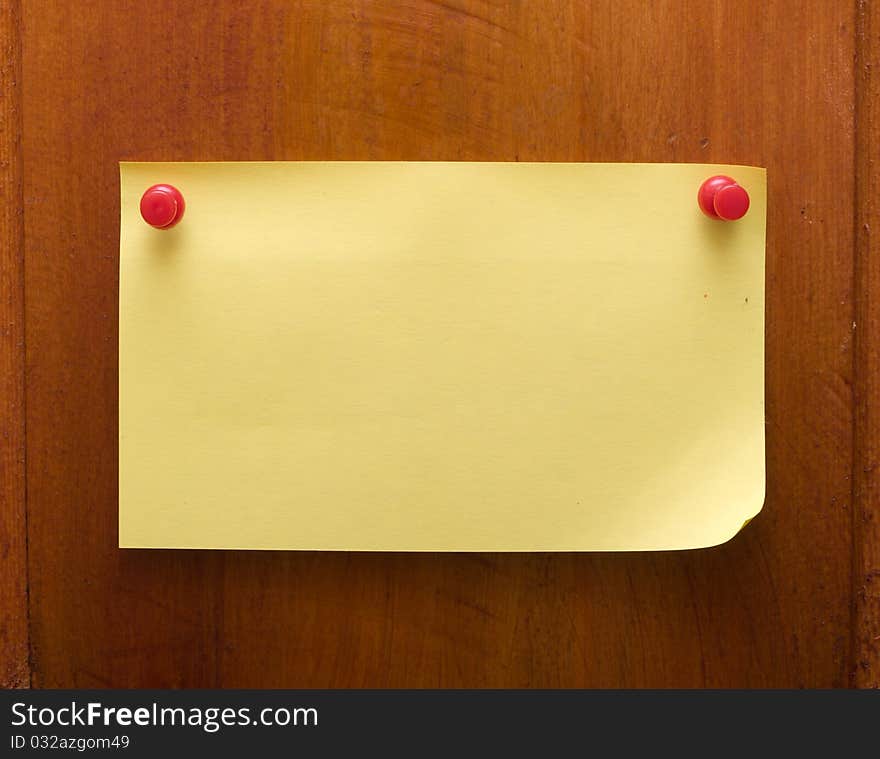 Yellow blank reminder on a wood desk with red push pin