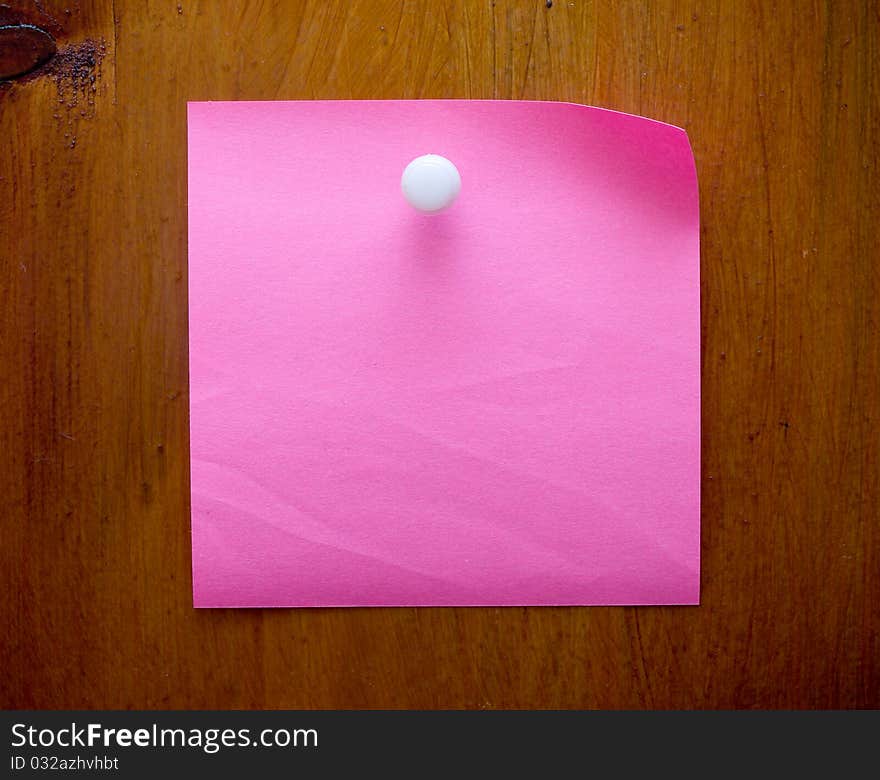 Pink blank reminder on a wood desk with white push pin