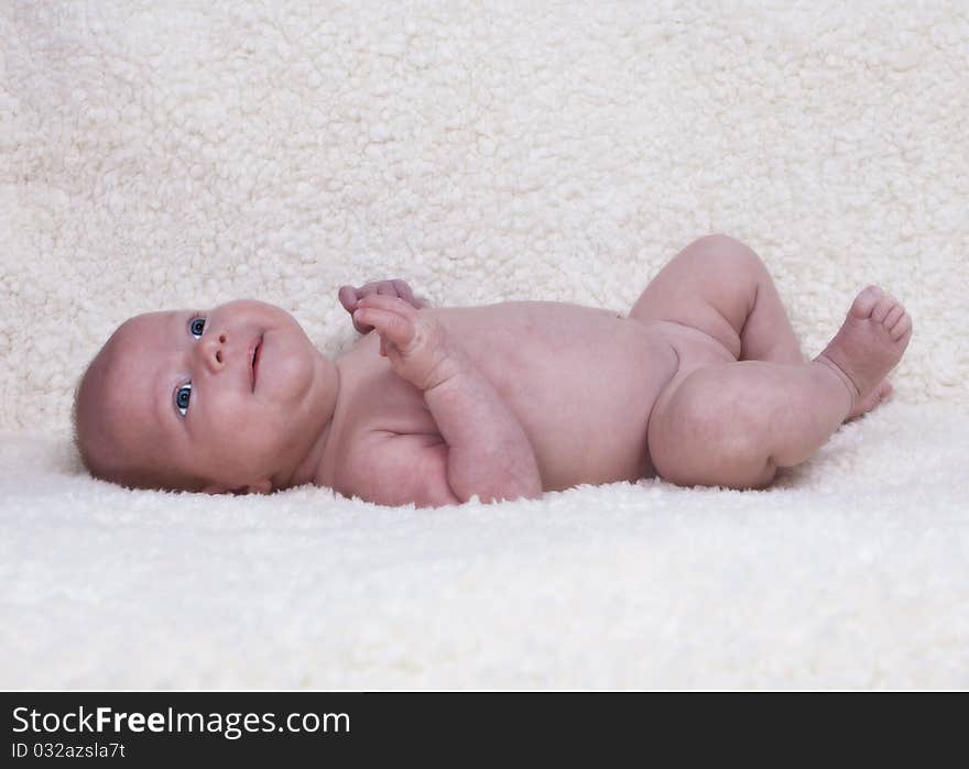 Little baby girl lying in bed with blue eyes wide open