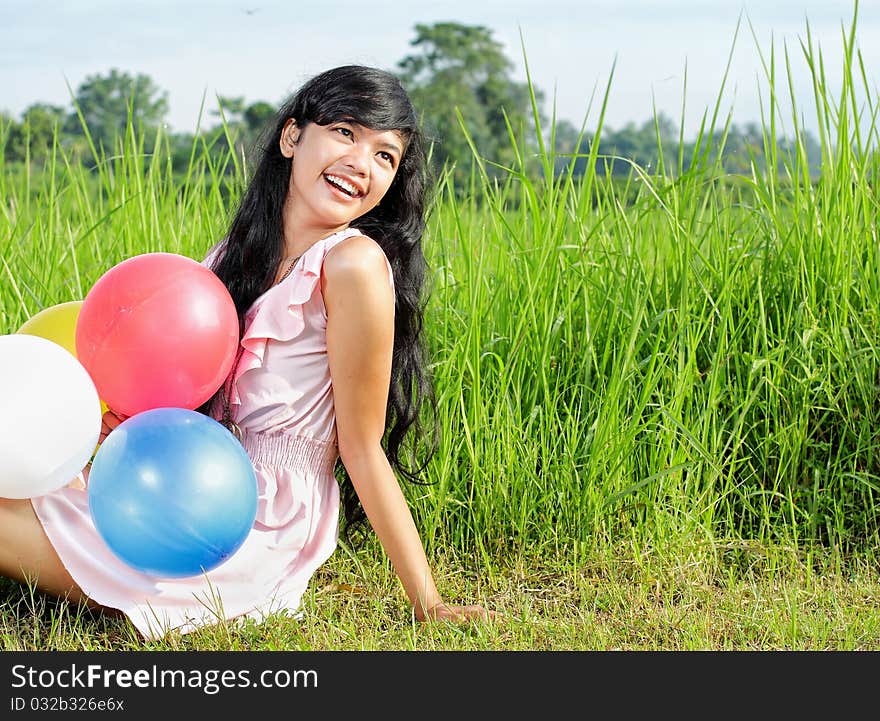 Beautiful teenage girl holding a bunch of colorful balloons in green nature. Beautiful teenage girl holding a bunch of colorful balloons in green nature