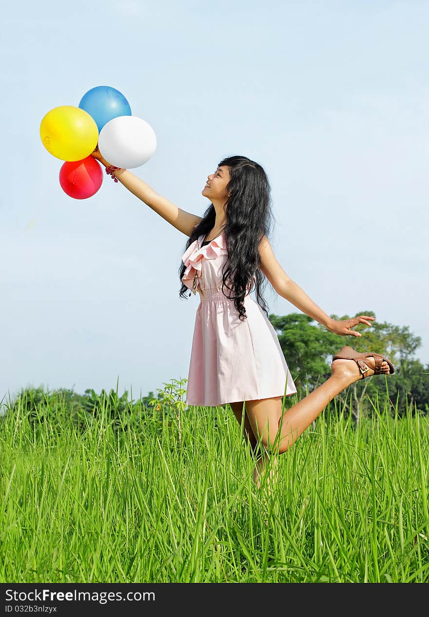 Young girl holding a bunch of colorful balloons in green nature. Young girl holding a bunch of colorful balloons in green nature