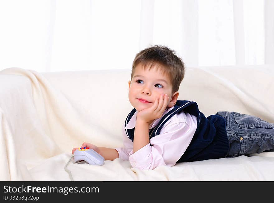 Little boy playing video games lying on the couch