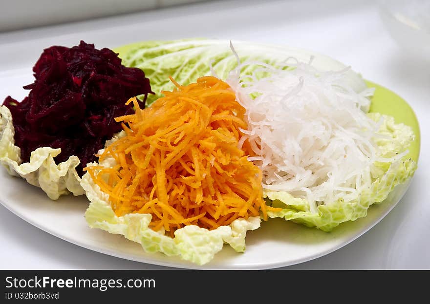 Boiled grated beets, carrot and redish daikon on a piece of lettuce. Boiled grated beets, carrot and redish daikon on a piece of lettuce