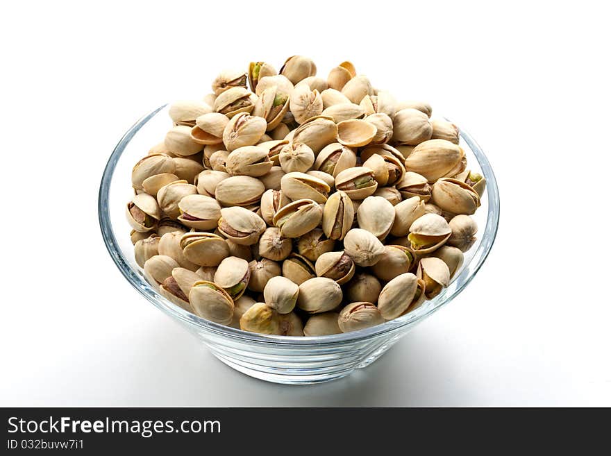 Pistachios nuts in glass bowl with white background