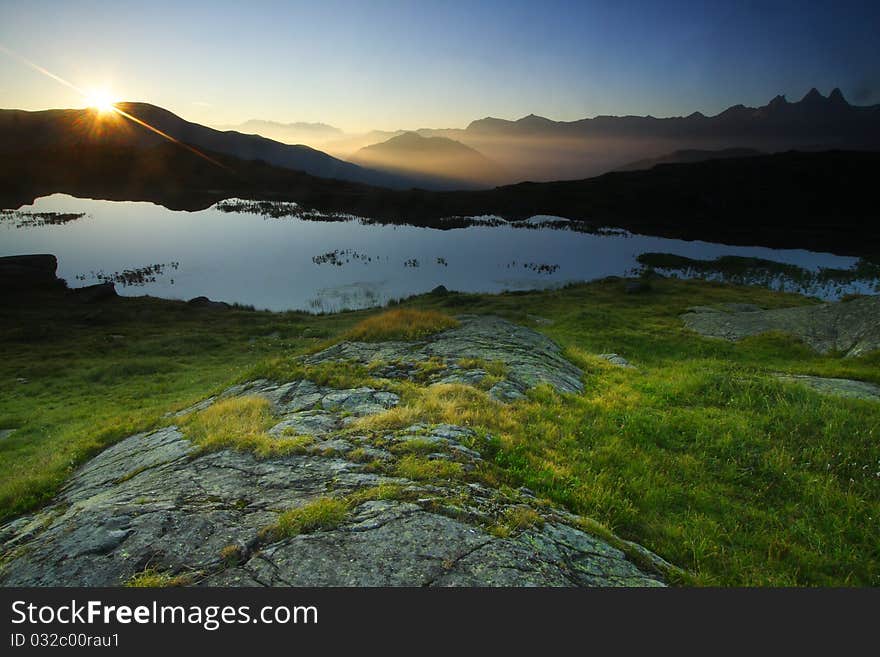 View over Guichard lake at sunrise in oisans near the famous col de la croix de fer, France. Aiguilles d'arve in the background. View over Guichard lake at sunrise in oisans near the famous col de la croix de fer, France. Aiguilles d'arve in the background.