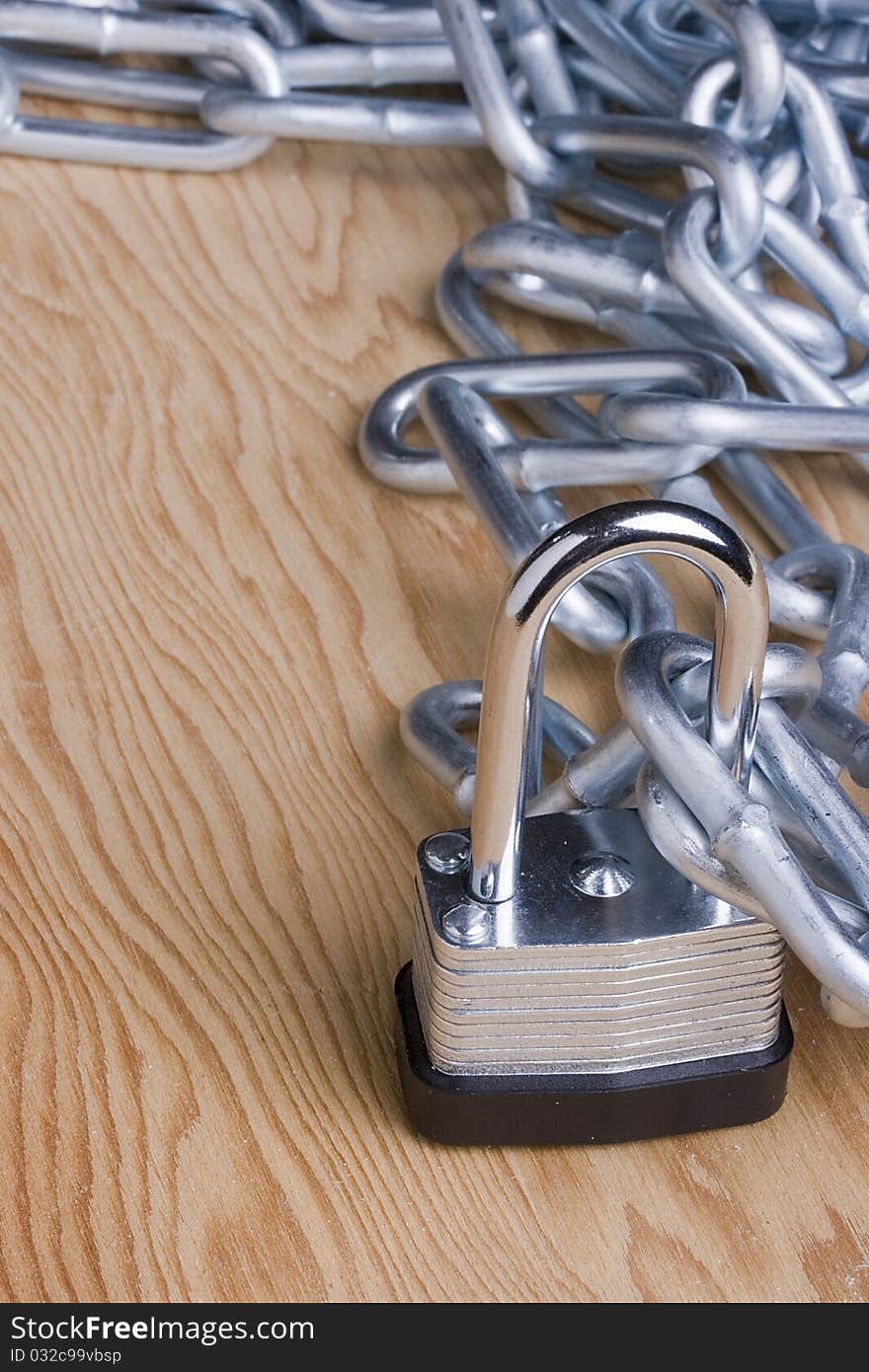 Metal lock and chain on a wooden background. Add your text to the background.