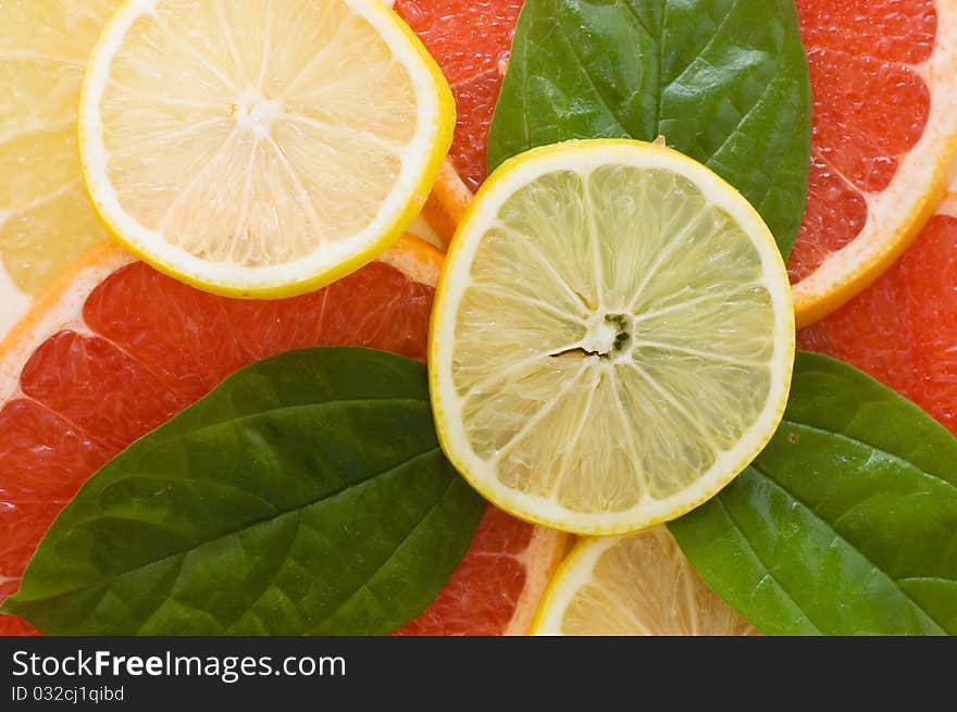 Fresh juicy grapefruits with green leafs close up