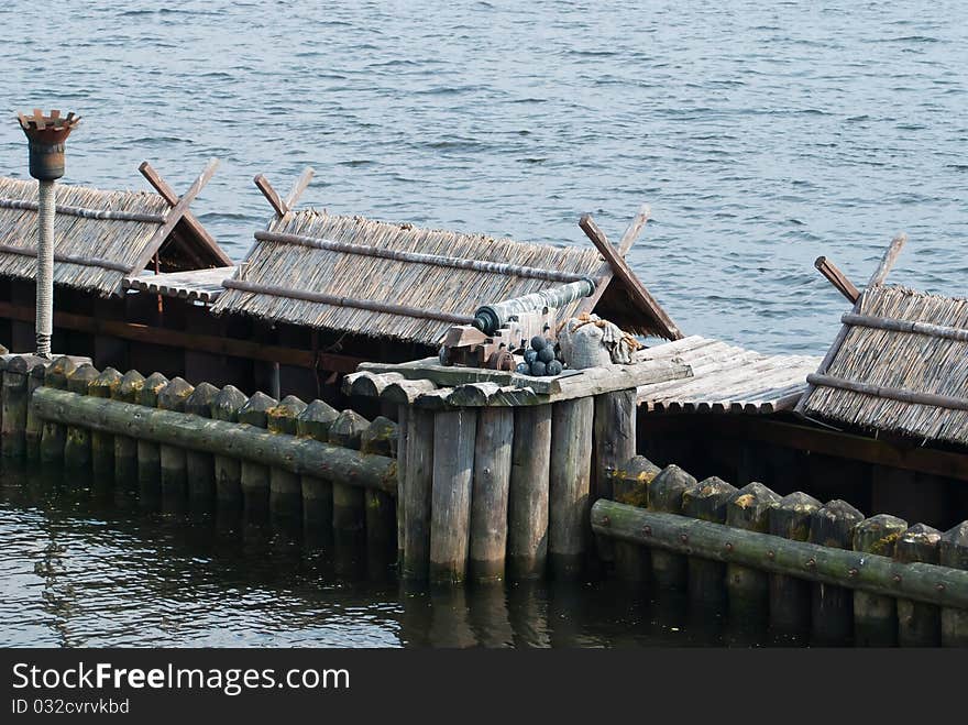 Old cannon on old wooden defenses with torches