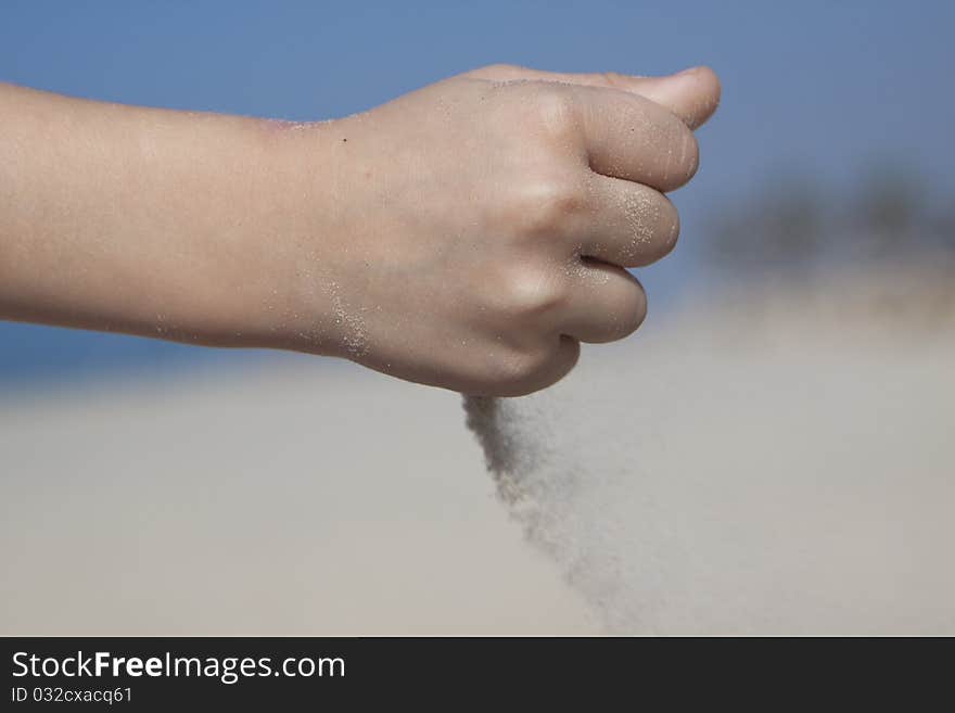 Small girl hand poring sand from her fist. Small girl hand poring sand from her fist