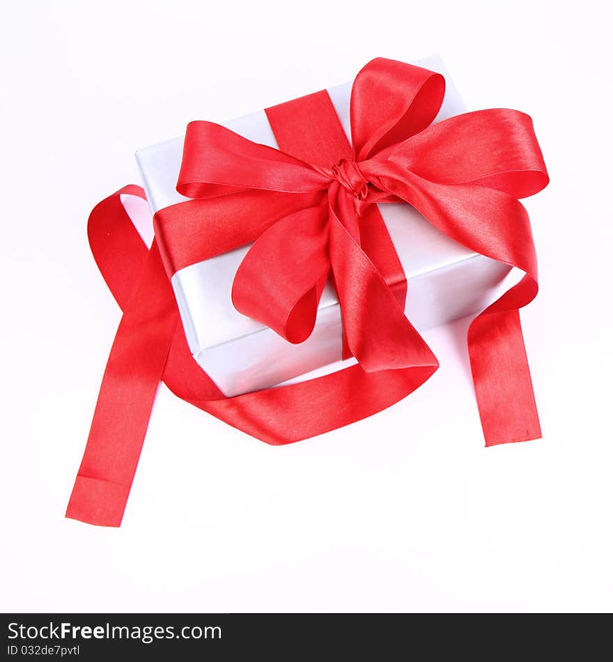 Gift in silver wrapping with a red bow on white background