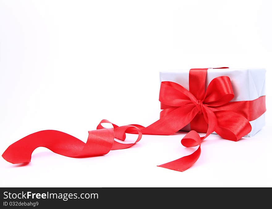 Gift in silver wrapping with a red bow on white background