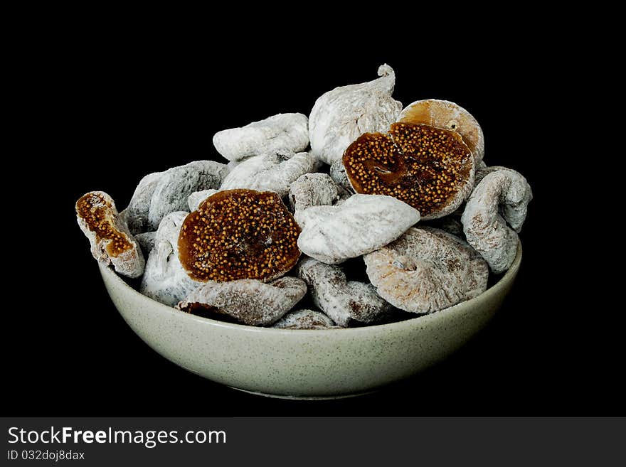 Dried figs in a ceramic bowl isolated on black