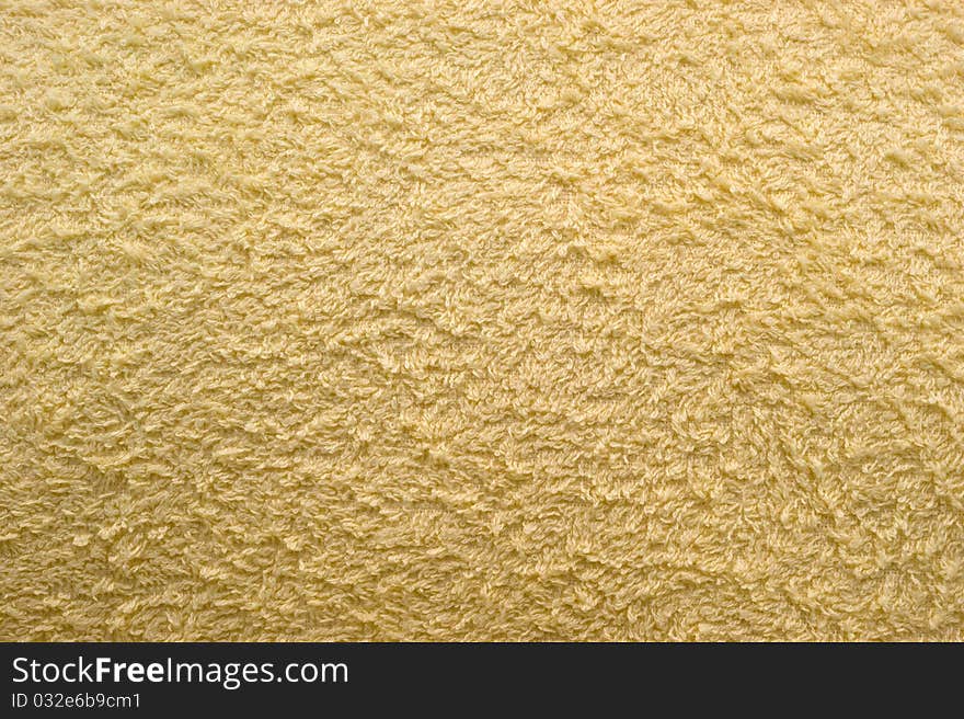 The background of textured light yellow synthetic fabric closeup