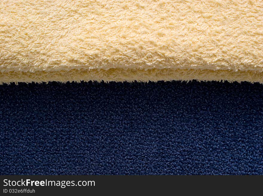 The background of textured light yellow and blue fabric closeup