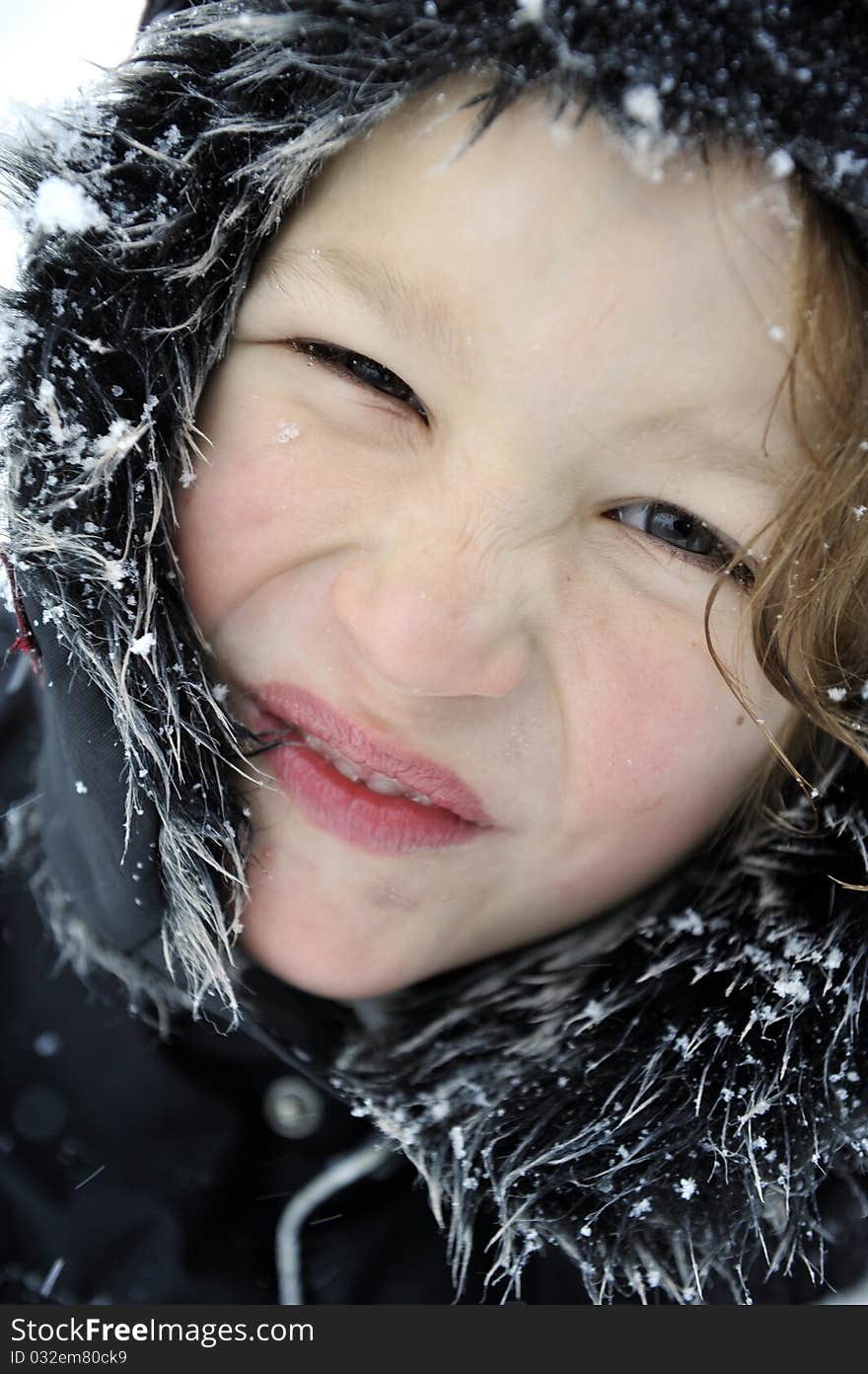 Portrait of a happy young boy outdoors in wintertime wearing a cap full of snow. Portrait of a happy young boy outdoors in wintertime wearing a cap full of snow