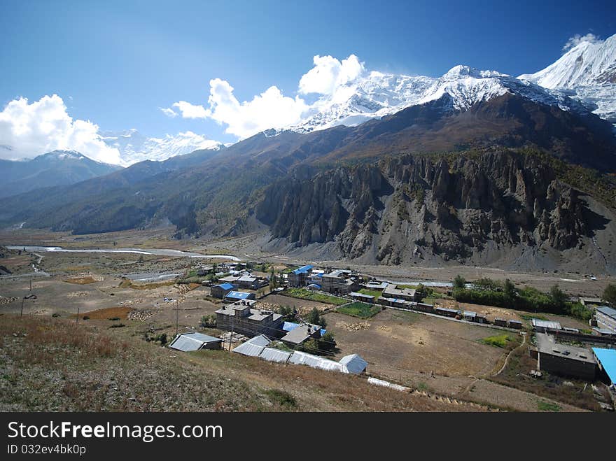 Nepali small village under snow peaks